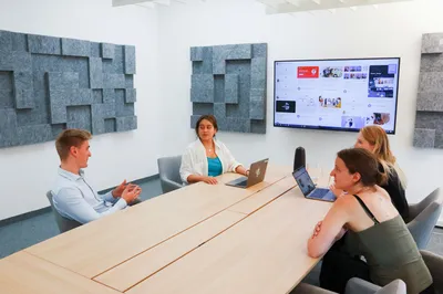 A team gathered around a conference table in front of a screen