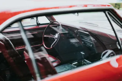 The dashboard and steering wheel inside a car with red upholstery
