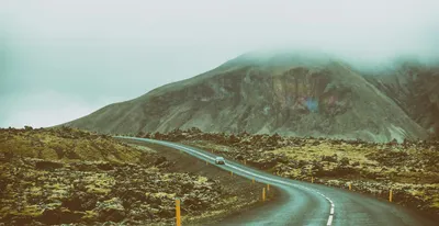 A road winding between rugged mountains beneath a cloudy sky